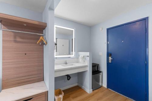 La salle de bains est pourvue d'un lavabo et d'une porte bleue. dans l'établissement Travelodge by Wyndham Fairplex Pomona, à Pomona
