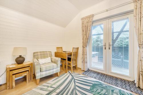 a living room with a table and a chair and a window at Ash Lodge in Ulverston
