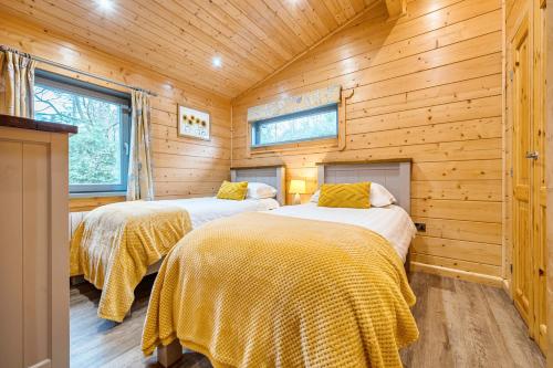 - une chambre avec 2 lits dans une cabane en bois dans l'établissement Elm Lodge, à Ulverston