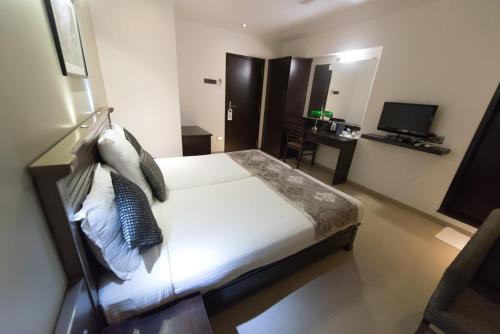 a bedroom with a bed and a desk and a television at Hotel Le Grande - Mumbai International Airport in Mumbai