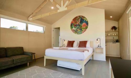 a bedroom with a bed and a chair and a couch at One O One Cabins, Waiheke Island in Oneroa