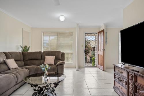 a living room with a couch and a tv at Swainson on Fontaine in Sellicks Beach