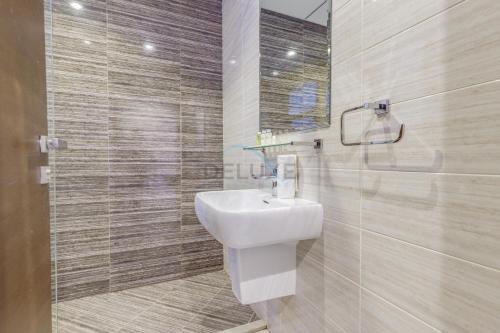 富查伊拉Grand 4BR Villa with Majestic Mountain and Sea Views, Assistant Room, and Private Pool, Just a Few Minutes Drive from Fujairah Finest Beaches and Camping Sites, Al Dana Island, Fujairah by Deluxe Holiday Homes的带白色水槽和淋浴的浴室