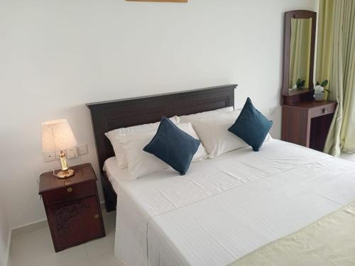 Un dormitorio con una cama con almohadas azules y blancas. en Seaside Escape Ocean Views Uswetakeiyawa, en Uswetakeiyawa