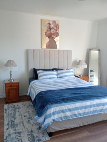 a bedroom with a large bed with a blue and white blanket at The Wee Hoose in Strand