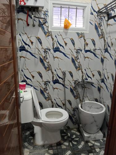a bathroom with a toilet and a fish patterned wall at Manggala Homestay Bromo in Ngadisari