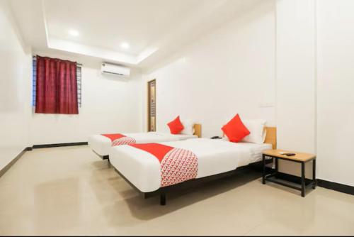 Duas camas num quarto branco com almofadas vermelhas em Sakthi Grand em Erode