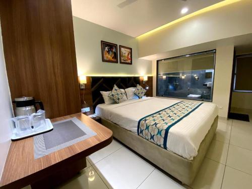 a hotel room with a large bed and a desk at Townhouse Vadodara Railway Junction Formerly Hotel Unique in Vadodara