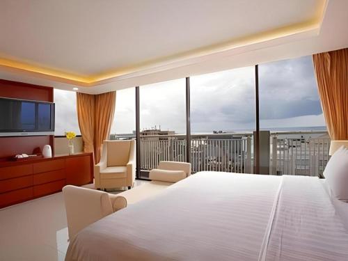 a bedroom with a large white bed and a balcony at Hotel Santika Makassar in Makassar