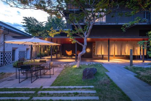 a patio with a table and chairs and a tree at Matsumoto Jujo in Matsumoto