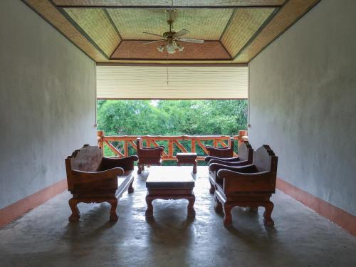 un soggiorno con sedie, tavolo e ampia finestra di Baan Khue Wieng Resort a Mae Sariang