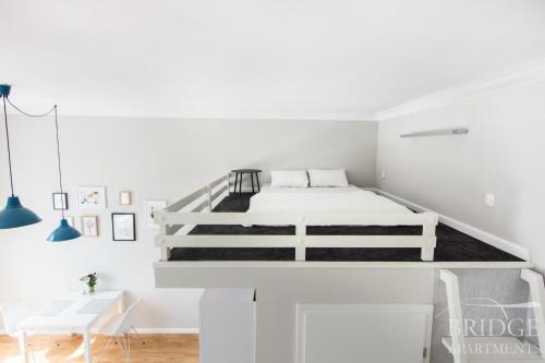 - une chambre blanche avec un lit blanc et un bureau dans l'établissement Bridge Apartments, à Cracovie