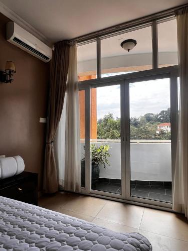 Schlafzimmer mit einer großen Glastür und einem Fenster in der Unterkunft Urban 2 Bedroom Serviced Apartment in Nakasero in Nalakonge