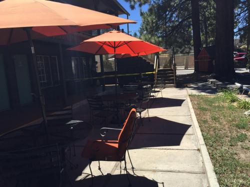 a group of tables and chairs with umbrellas on a sidewalk at Robinhood Resort in Big Bear Lake
