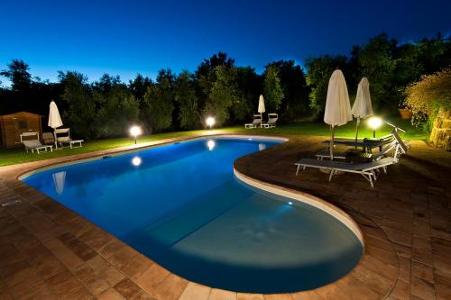 a swimming pool at night with chairs and umbrellas at Cerchio Verde in Pitigliano