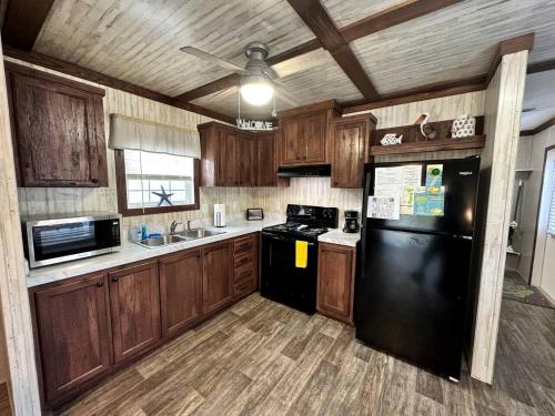 eine Küche mit Holzschränken und einem schwarzen Kühlschrank in der Unterkunft Cozy Cottage with River Access for a Fun-Filled Getaway by the Rainbow River in Florida in Dunnellon