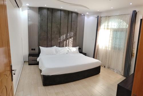 ein Schlafzimmer mit einem großen weißen Bett mit einem hölzernen Kopfteil in der Unterkunft منتجع الكناري in Ta'if