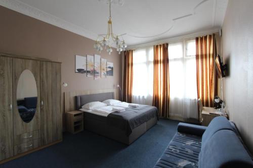 a bedroom with a bed and a couch and a mirror at City Hotel Gotland in Berlin