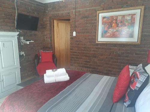 ein Schlafzimmer mit einem Bett und einer Ziegelwand in der Unterkunft Sundown Lodge and Confrence in Aliwal North