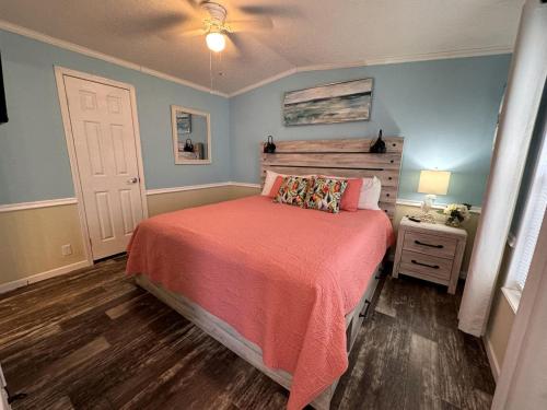 ein Schlafzimmer mit einem Bett mit einer orangefarbenen Tagesdecke und einem Tisch in der Unterkunft Modern Cottage with Incredible Amenities and Rainbow River Access near Dunnellon, Florida in Dunnellon