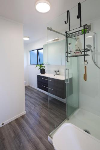 a bathroom with a glass shower and a sink at Seaviews and a stroll to Whanagaumu bay in Whangarei