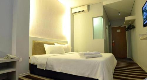 a bedroom with a white bed with towels on it at First Residence Hotel Kemaman in Kampong Gong Pauh