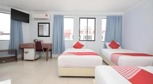 Cette chambre comprend 3 lits et un bureau. dans l'établissement OYO 969 Hotel Pantai View, à Victoria