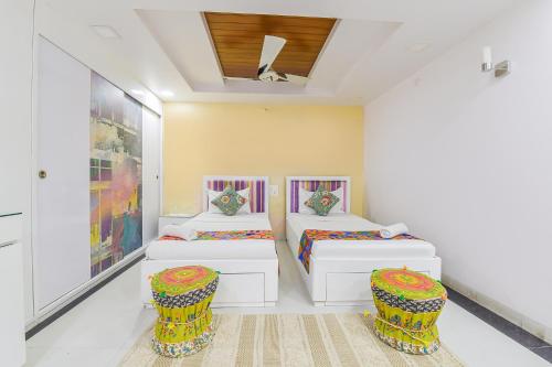 a bedroom with two beds and two stools at FabHotel Pink Cozzy in Jaipur