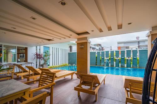 an outdoor patio with tables and chairs and a swimming pool at Ratana Hotel Rassada, PHUKET TOWN- SHA Extra Plus in Phuket