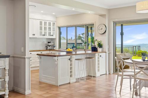 eine Küche mit weißen Schränken und einer Uhr an der Wand in der Unterkunft Coastview Manor - Family Hinterland Retreat in Valdora