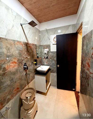 a bathroom with a toilet and a sink and a black door at Hotel Pratyaksh Darshan in Varanasi
