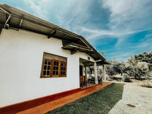 Una casa blanca con una ventana en el costado. en Hiriketiya Lima Homestay, en Dikwella