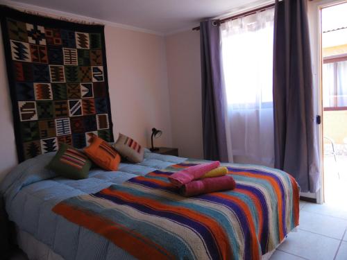 een slaapkamer met een bed met kleurrijke kussens erop bij Hostal Campo Base in San Pedro de Atacama