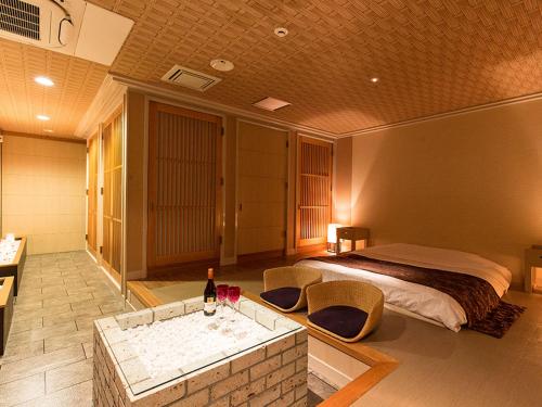 a bedroom with a bed and a tub with a bottle of wine at HOTEL PARIET Nakagawa - Adult Only in Fukuoka