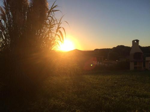 a sunset in a field with the sun setting in the background at Rosanna House in Bombarde Beach in Alghero