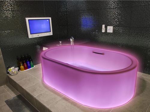 eine große rosa Badewanne in einem Badezimmer mit Fernseher in der Unterkunft HOTEL PARIET Nakagawa - Adult Only in Fukuoka