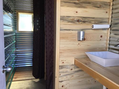 a bathroom with a white sink and wooden walls at Lupine Cabin, Glamour Camping, Stunning Skies and Sunrise Views in Monticello