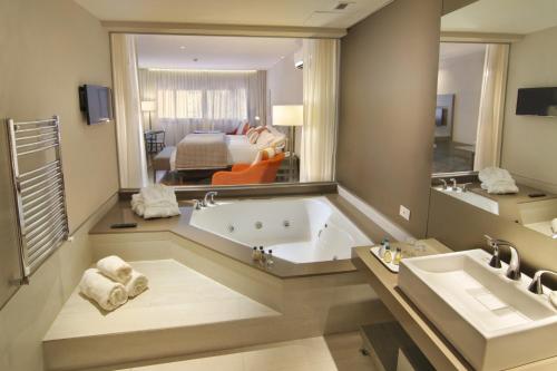 a large bathroom with a tub and a large mirror at Altos de Belgrano Hotel Cabañas Golf y Spa in Villa General Belgrano