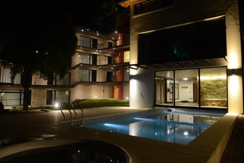 una piscina frente a un edificio por la noche en El Oasis Apart Hotel en San Martín de los Andes