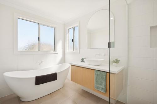 une salle de bain blanche avec une baignoire et un lavabo dans l'établissement Scarp n Sea, Sauna Views & Serene Coastal Comfort, à Falcon