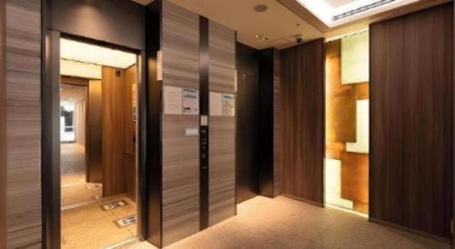 un pasillo con puertas de madera en un edificio en KEIKYU EX INN Hamamatsucho Daimon-Station (Tokyo), en Tokio