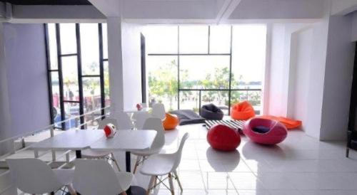 ein Raum mit weißen Tischen und Stühlen und Fenstern in der Unterkunft Chic-Chidkong Boutique Hotel in Nakhon Phanom