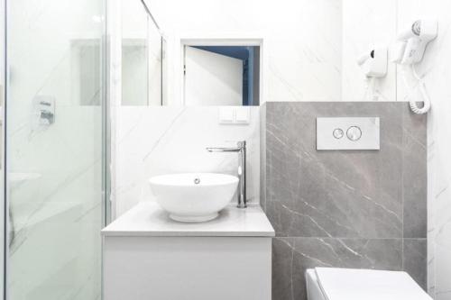 een witte badkamer met een wastafel en een douche bij Golden Prime Apartments - Mennica Residence - Luxury in City Center in Warschau