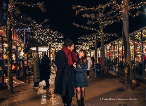 a man and a woman walking down a street with christmas lights at Hotel Kö59 Düsseldorf - Member of Hommage Luxury Hotels Collection in Düsseldorf