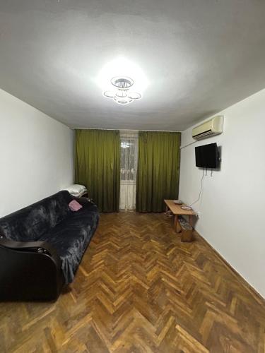 Una sala de estar con un sofá negro y un televisor. en Apartament Craiova Târgul de Crăciun zona centrală, en Craiova