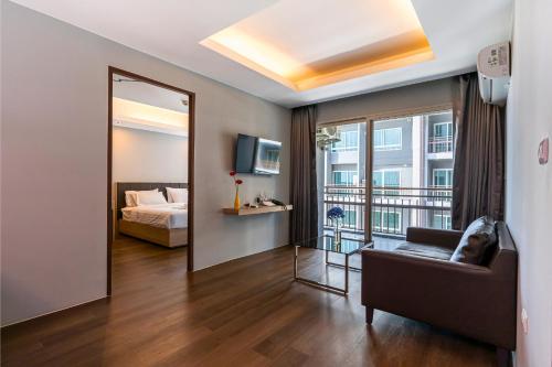 ein Wohnzimmer mit einem Bett und einem Spiegel in der Unterkunft Tisha Hotel ABAC Bangna in Bang Bo