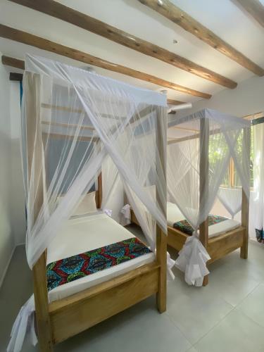 a bedroom with two bunk beds with mosquito nets at Nakupenda paje villa in Paje