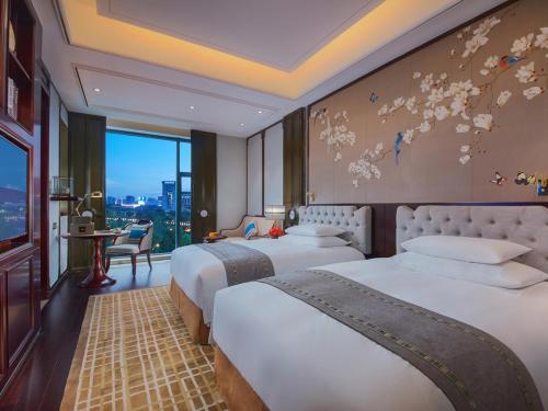 a hotel room with two beds and a window at New Century Grand Hotel Zunyi in Zunyi
