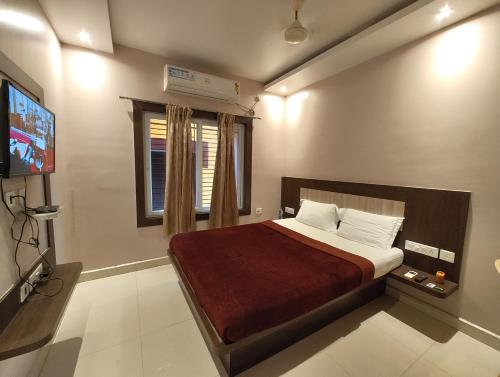 Un dormitorio con una cama y un televisor. en Hotel HTN Stay Puri Near Golden Beach and Temple - Air-Conditioned With Lift #wi-fi And Parking Facilities - Spacious Room - Prime Location Book It Early, en Puri