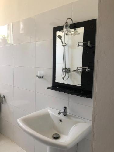 a bathroom with a white sink and a mirror at Villa Ranuka in Unawatuna
